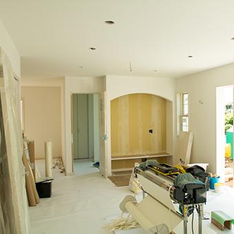 家の中を撮影した写真。白い内壁、床、天井の屋内には、工事に使われる様々な機材が置かれている。